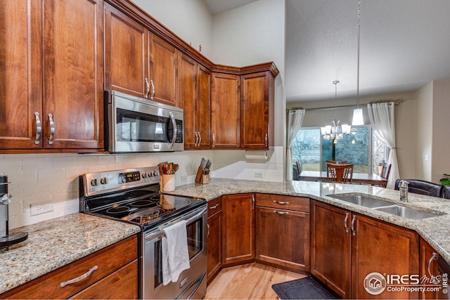 kitchen with hanging light fixtures, sink, appliances with stainless steel finishes, a notable chandelier, and light stone counters