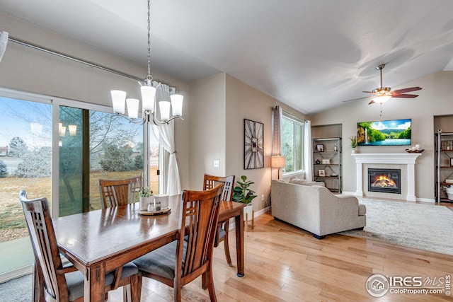 dining area featuring ceiling fan with notable chandelier, light hardwood / wood-style floors, and lofted ceiling