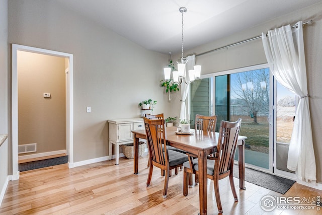 dining area with light hardwood / wood-style flooring and a notable chandelier