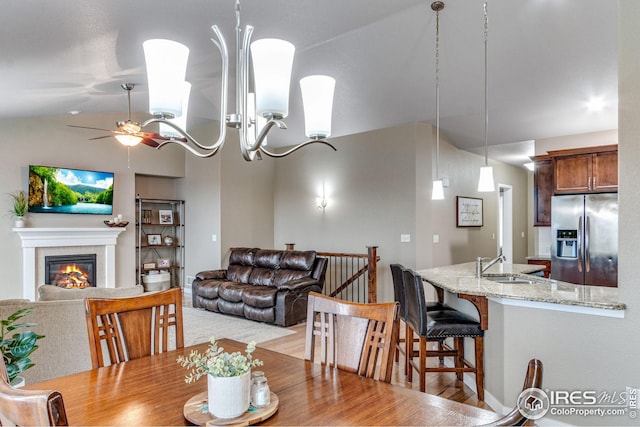 dining area with lofted ceiling, sink, ceiling fan with notable chandelier, and light wood-type flooring