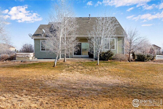 back of property with a lawn, a patio area, and a hot tub