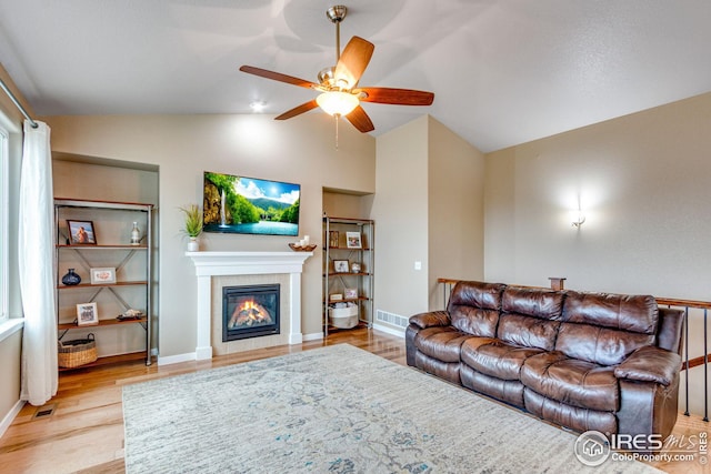 living room with a fireplace, light wood-type flooring, ceiling fan, and lofted ceiling