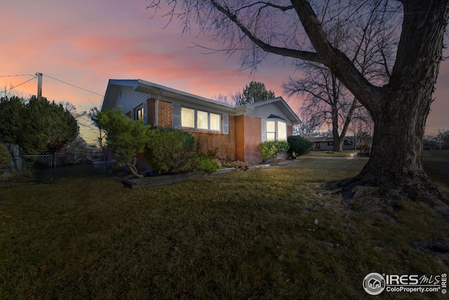 property exterior at dusk featuring a lawn