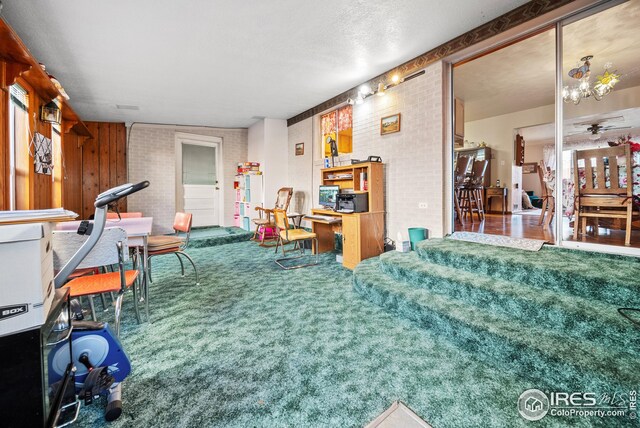 interior space with wood walls, carpet, and ceiling fan with notable chandelier