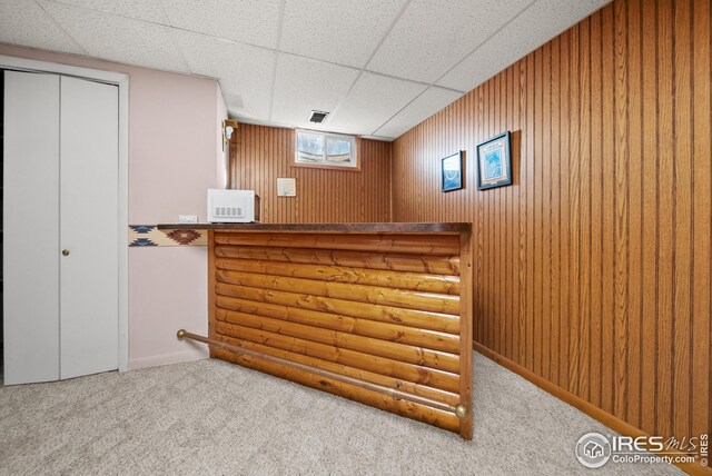 bar with wood walls, a drop ceiling, and carpet floors