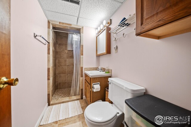 bathroom with a paneled ceiling, tile patterned floors, a shower with curtain, vanity, and toilet