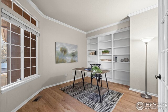 office space with baseboards, ornamental molding, visible vents, and wood finished floors
