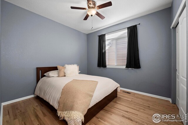 bedroom featuring baseboards, visible vents, wood finished floors, and a ceiling fan