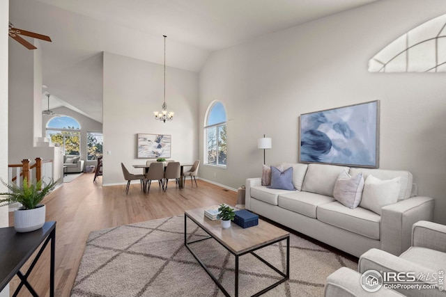living room with ceiling fan with notable chandelier, wood finished floors, baseboards, and a wealth of natural light