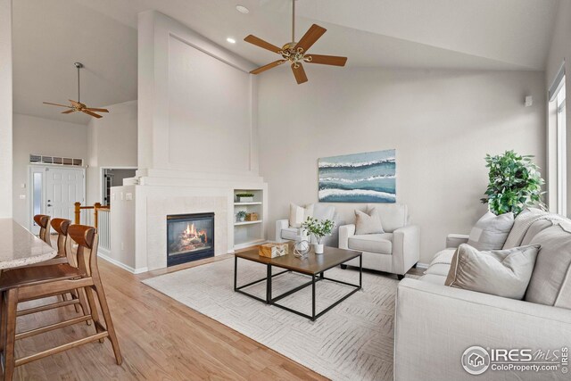 living room with high vaulted ceiling, a tile fireplace, light wood-style flooring, ceiling fan, and recessed lighting