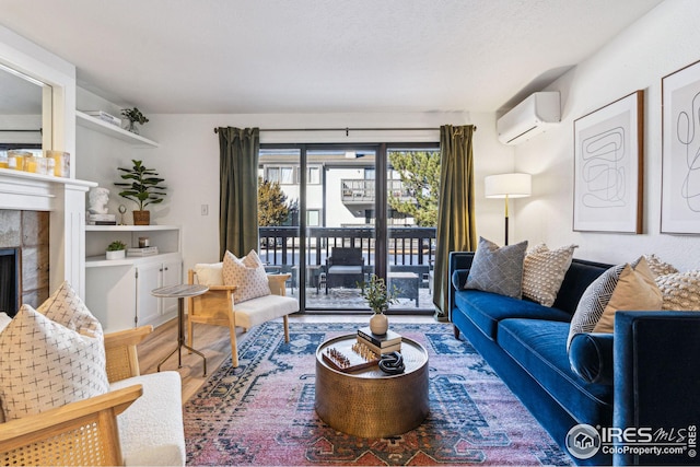 living room featuring a tile fireplace, wood-type flooring, a textured ceiling, and an AC wall unit