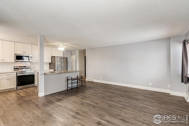 kitchen featuring white cabinetry, decorative backsplash, stainless steel appliances, and dark wood finished floors