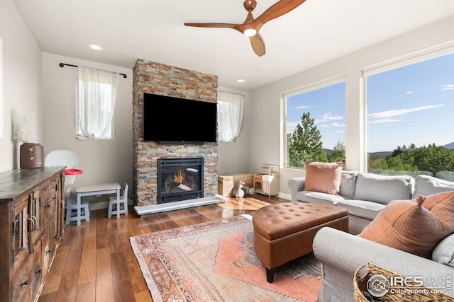 living area featuring baseboards, hardwood / wood-style flooring, ceiling fan, a fireplace, and recessed lighting