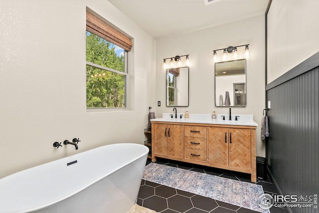 bathroom with a freestanding tub, double vanity, a sink, and tile patterned floors