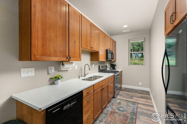 kitchen with a sink, visible vents, baseboards, light countertops, and black appliances