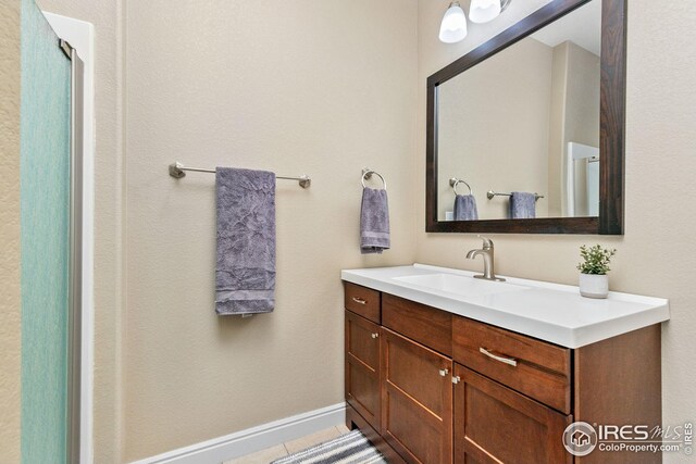 full bathroom with an enclosed shower, baseboards, and vanity