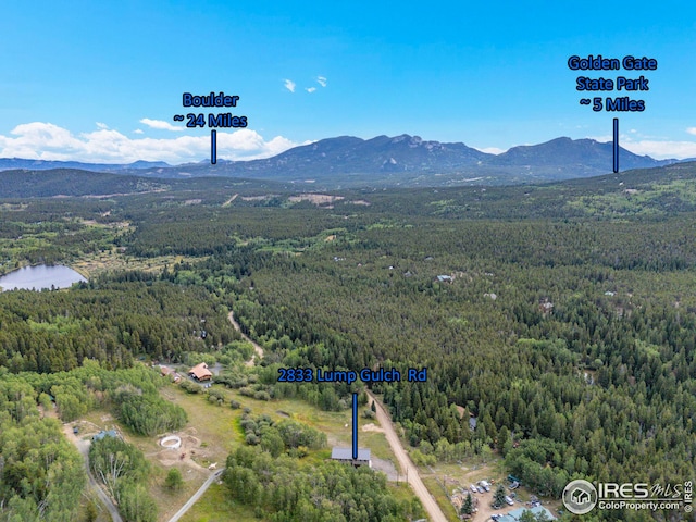 birds eye view of property featuring a water and mountain view and a wooded view