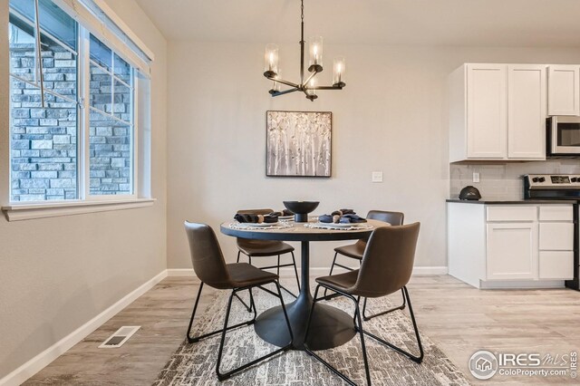 dining space featuring light wood-type flooring and a chandelier