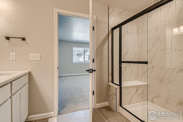 bathroom with vanity, a shower with shower door, and a textured ceiling