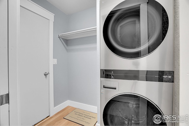 laundry room with hardwood / wood-style flooring and stacked washer and dryer