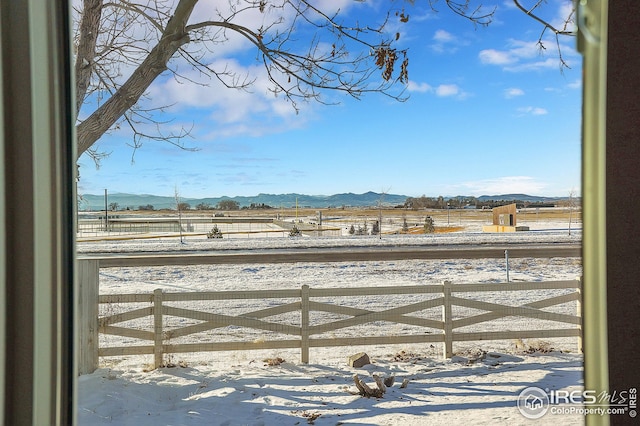 yard layered in snow featuring a mountain view and a rural view