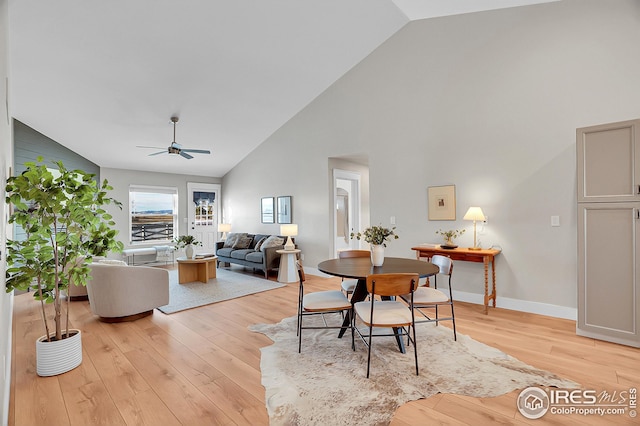 dining space featuring light wood-type flooring, high vaulted ceiling, and ceiling fan