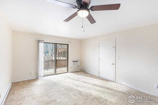 carpeted spare room with a wall unit AC and ceiling fan