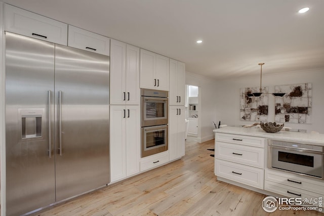 kitchen featuring light stone counters, ornamental molding, stainless steel appliances, light hardwood / wood-style flooring, and white cabinetry