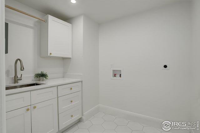 washroom featuring hookup for an electric dryer, hookup for a washing machine, cabinets, sink, and light tile patterned floors