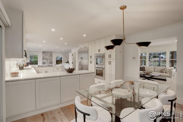 kitchen featuring kitchen peninsula, white cabinets, stainless steel appliances, and light hardwood / wood-style floors