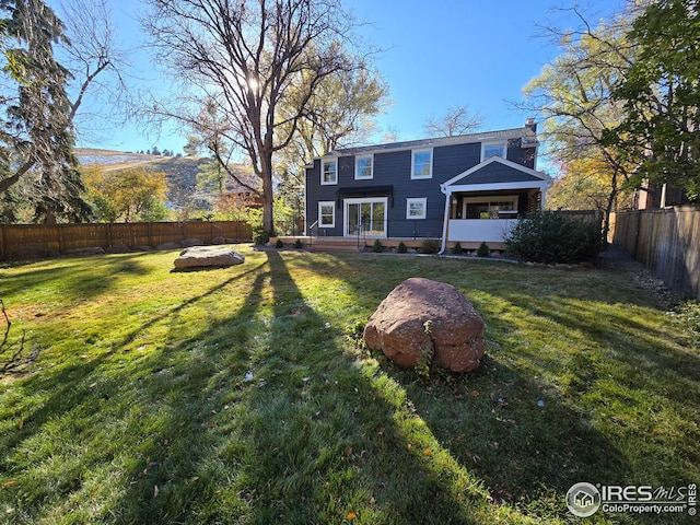 rear view of house with a mountain view and a yard