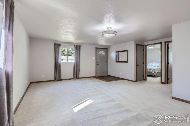 entrance foyer featuring light carpet and a textured ceiling