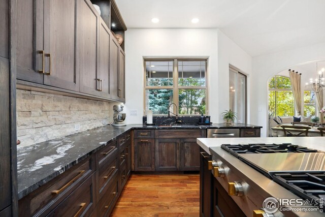 kitchen featuring sink, light hardwood / wood-style flooring, dark stone countertops, a chandelier, and stainless steel gas stovetop