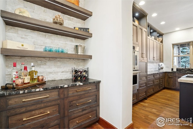 kitchen with dark hardwood / wood-style floors, sink, dark stone counters, and tasteful backsplash