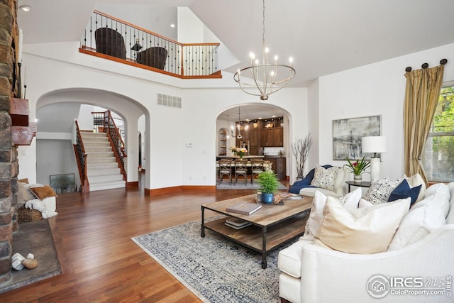 living room with a notable chandelier, dark hardwood / wood-style flooring, and a towering ceiling