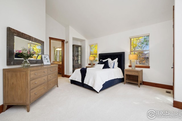 bedroom with ensuite bathroom, high vaulted ceiling, and light colored carpet