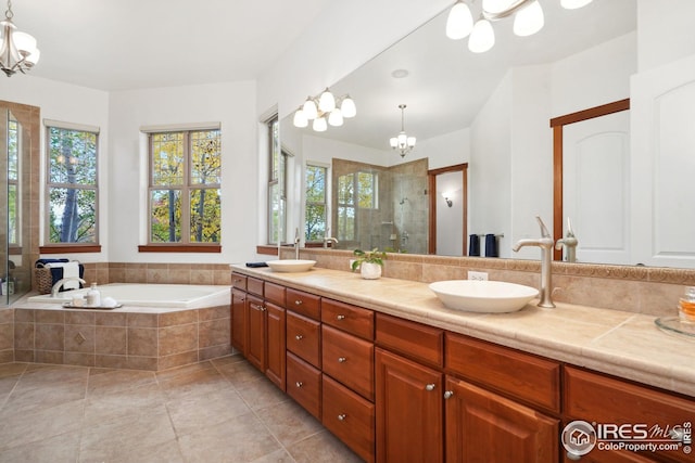 bathroom with tile patterned flooring, vanity, independent shower and bath, and a notable chandelier
