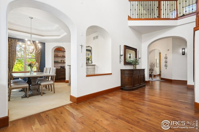 interior space featuring hardwood / wood-style flooring, a raised ceiling, and a chandelier