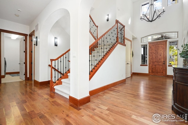 entryway with light wood-type flooring, a high ceiling, and an inviting chandelier