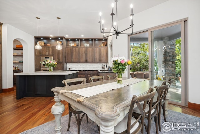 dining room with sink, built in features, dark wood-type flooring, and a chandelier