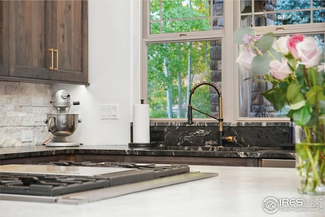 details featuring tasteful backsplash, dark brown cabinets, and stainless steel gas cooktop