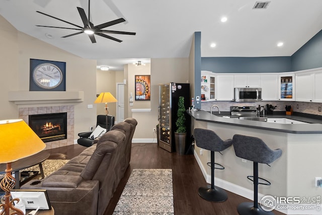 living room featuring lofted ceiling, dark hardwood / wood-style flooring, sink, and a tile fireplace