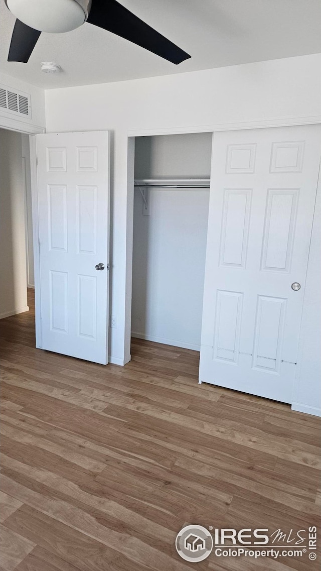 unfurnished bedroom with wood-type flooring, a closet, and ceiling fan