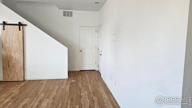 interior space with a barn door and wood-type flooring