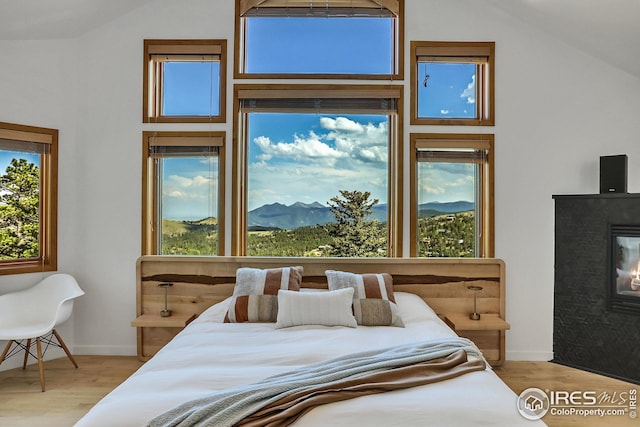 bedroom featuring a mountain view, wood finished floors, a fireplace, and vaulted ceiling