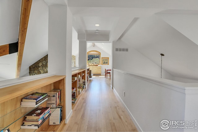 corridor featuring lofted ceiling, baseboards, visible vents, and light wood finished floors