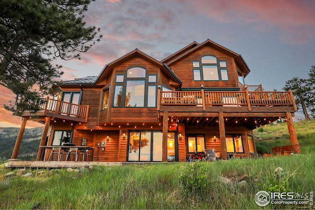 back of property at dusk featuring a wooden deck