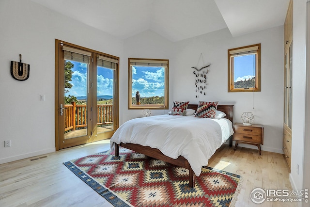 bedroom with access to exterior, light wood finished floors, baseboards, and lofted ceiling