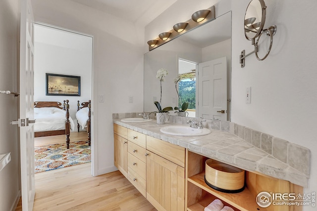 full bath featuring a sink, connected bathroom, wood finished floors, and double vanity