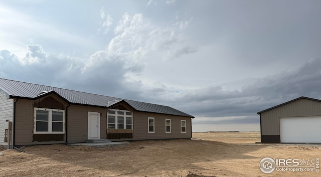 view of front facade with a garage, an outbuilding, and metal roof